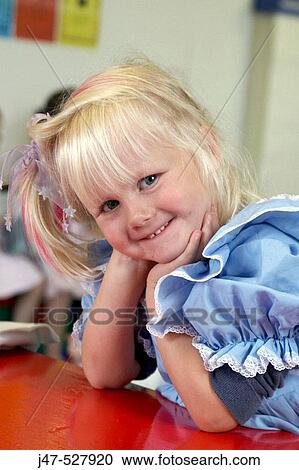 Stock Image - 4 year old girl, sitting at nursery, smiling. Fotosearch