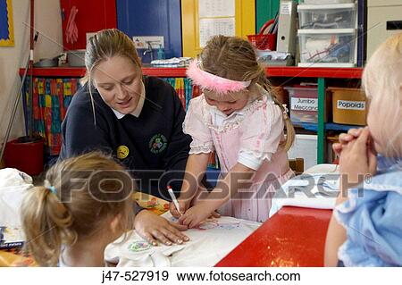 4 year old girl, sitting drawing with the teacher at nursery, smiling View Large Photo Image Stock Photo - 4 year old girl, sitting drawing with the teacher at nursery, smiling. Fotosearch