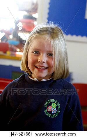Stock Image - 4 year old girl smiling into camera at nursery. Fotosearch