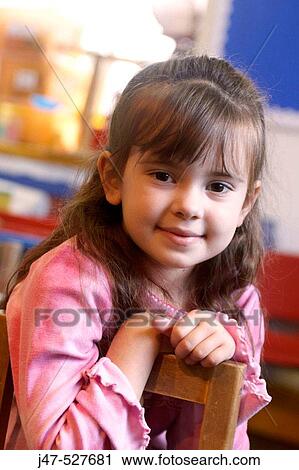 Stock Image - 4 year old girl smiling into camera at nursery,. Fotosearch