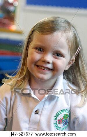 Stock Photo - 4 year old girl smiling into camera at nursery,. Fotosearch