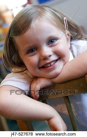 4 year old girl smiling into camera at nursery, leaning over the back of a chair View Large Photo Image Stock Photo - 4 year old girl smiling into camera at nursery, leaning over the back of a chair. Fotosearch