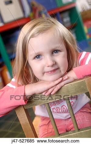 4 year old girl smiling into camera at nursery, with her chin resting on her hands View Large Photo Image Stock Photography - 4 year old girl smiling into camera at nursery, with her chin resting on her hands. Fotosearch