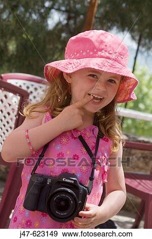 Stock Photo - 4 year old girl smiling into camera, holding a camera round her neck. Fotosearch