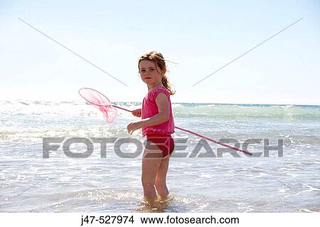 4 year old girl standing in the sea with a fishing net View Large Photo Image Picture - 4 year old girl standing in the sea with a fishing net. Fotosearch