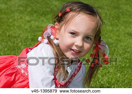 Stock Photo - 4 years old girl in red dress sitting on the grass.. Fotosearch