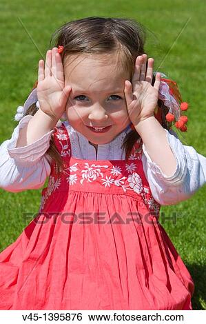 Stock Photograph - 4 years old girl in red dress sitting on the grass.. Fotosearch