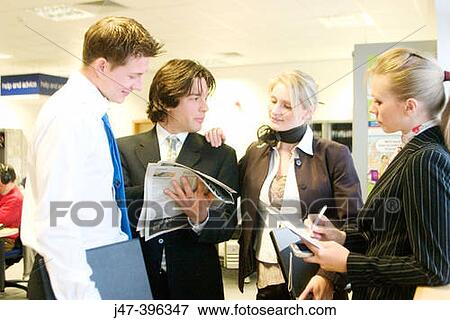 4 young business people standing in a group looking at a newspaper View Large Photo Image Stock Photo - 4 young business people standing in a group looking at a newspaper. Fotosearch