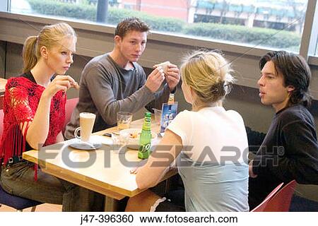 4 young people sitting in a cafe together having lunch View Large Photo Image Stock Image - 4 young people sitting in a cafe together having lunch. Fotosearch