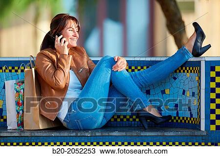 Stock Image - 40 Woman talking on the phone. Shopping on the street. Donostia. San Sebastian. Gipuzkoa. Basque Country. Spain.. Fotosearch