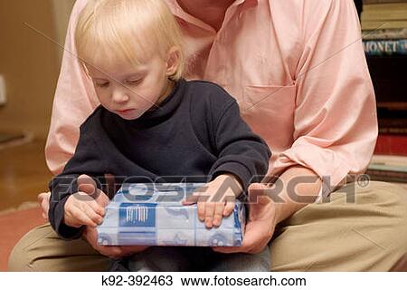 40 year old father holds his 2 year old son as the child opens a Channuka present View Large Photo Image Stock Image - 40 year old father holds his 2 year old son as the child opens a Channuka present. Fotosearch