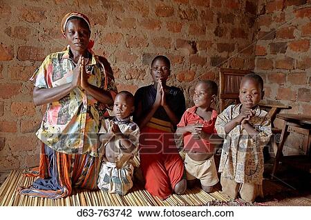 Stock Image - 40UGANDA In the home of Najjemba Teopista, Kasaayi village, Kayunga District Family praying, from left to right: Teopista, Nakata Maria Goretti, 7, Nankinda Faustea, 13, Waswa Joseph, 7, Lugya Kevin, 5, grandson. Fotosearch