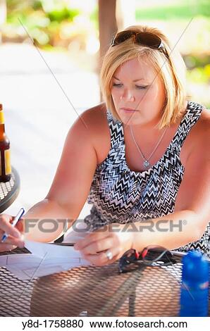 45 years old woman writing a check in outdoor restaurant View Large Photo Image Stock Image - 45 years old woman writing a check in outdoor restaurant. Fotosearch