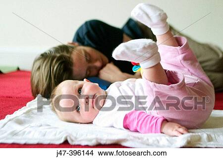 Picture - 5 month old baby girl lying in front of sleeping mother. Fotosearch