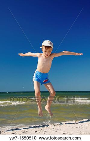 Stock Image - 5 year old boy jumping on a beach. Fotosearch