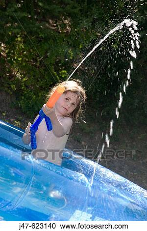 5 year old girl sitting in a swimming pool firing water out of a water pistol, smiling View Large Photo Image Stock Image - 5 year old girl sitting in a swimming pool firing water out of a water pistol, smiling. Fotosearch