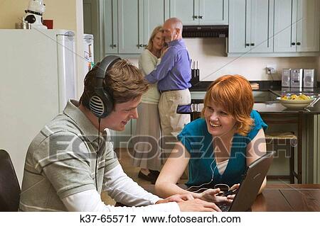 50-60 y/o couple dancing to music from stereo/radio in kitchen with teen/adult children sitting in dining room listening to music on laptop & ipod. View Large Photo Image Stock Photo - 50-60 y/o couple dancing to music from stereo/radio in kitchen with teen/adult children sitting in dining room listening to music on laptop & ipod.. Fotosearch