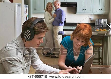50-60 y/o couple dancing to music from stereo/radio in kitchen with teen/adult children sitting in dining room listening to music on laptop & ipod. View Large Photo Image Stock Photography - 50-60 y/o couple dancing to music from stereo/radio in kitchen with teen/adult children sitting in dining room listening to music on laptop & ipod.. Fotosearch