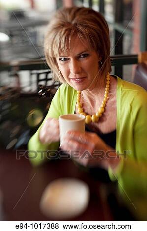 50 year old woman in a coffee shop looking at the camera holding a coffee cup between her hands. View Large Photo Image Stock Photo - 50 year old woman in a coffee shop looking at the camera holding a coffee cup between her hands.. Fotosearch