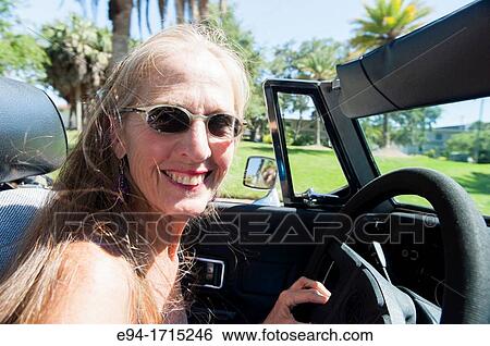 57 year old woman with long hair blowing in her face driving her MG convertible car View Large Photo Image Stock Photograph - 57 year old woman with long hair blowing in her face driving her MG convertible car. Fotosearch