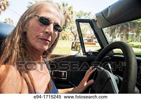 57 year old woman with long hair blowing in her face driving her MG convertible car View Large Photo Image Stock Photography - 57 year old woman with long hair blowing in her face driving her MG convertible car. Fotosearch