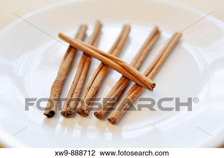Stock Image - 6 cinnamon sticks on white plate. Fotosearch