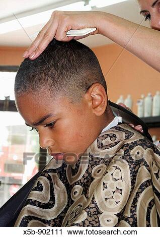 Stock Image - 6 year old African American boy getting a hair cut Making a face. Fotosearch