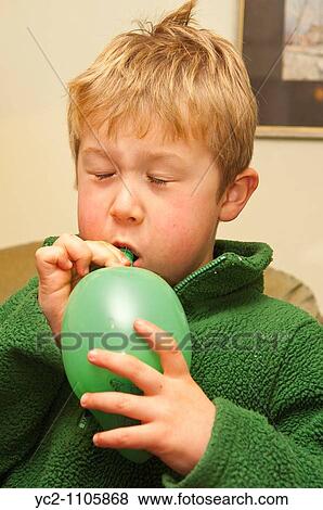 Stock Photo - 6 year old boy blowing up a balloon in the UK. Fotosearch