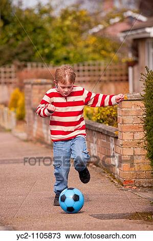6 year old boy playing football in the steet in the Uk View Large Photo Image Stock Image - 6 year old boy playing football in the steet in the Uk. Fotosearch