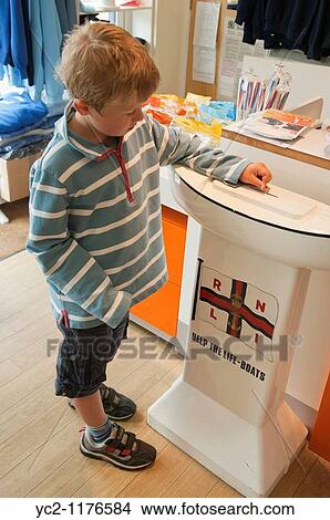 6 year old boy putting money in a lifeboat RNLI charity box in Aldeburgh, Suffolk, England, Great Britain, Uk View Large Photo Image Picture - 6 year old boy putting money in a lifeboat RNLI charity box in Aldeburgh, Suffolk, England, Great Britain, Uk. Fotosearch