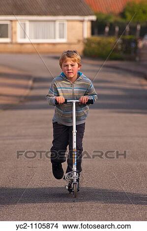 6 year old boy scooting on his scooter in the Uk View Large Photo Image Picture - 6 year old boy scooting on his scooter in the Uk. Fotosearch