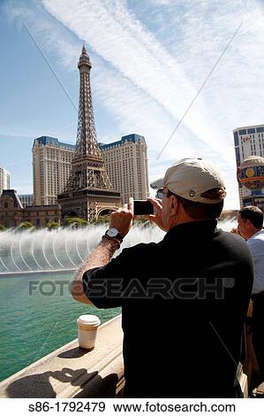 60ish Man Photographing the Water Fountain Show at the Bellagio Hotel, Las Vegas, NV, using his iPhone View Large Photo Image Stock Photo - 60ish Man Photographing the Water Fountain Show at the Bellagio Hotel, Las Vegas, NV, using his iPhone. Fotosearch