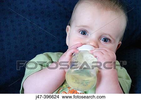 7 month old baby holding a bottle, looking into camera View Large Photo Image Picture - 7 month old baby holding a bottle, looking into camera. Fotosearch