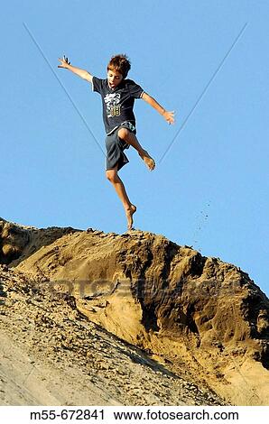 Stock Image - 7 year old boy playing on sand dunes. Oregon. USA.. Fotosearch