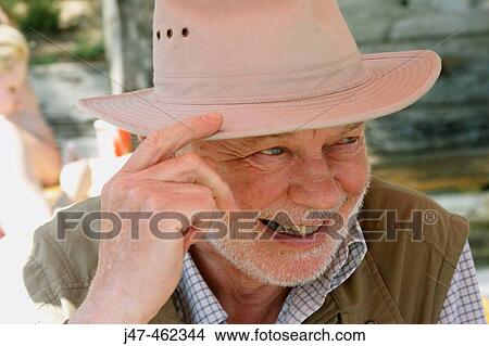 Picture - 70 year old man outside in the sunshine wearing a hat, smiling off camera. Fotosearch