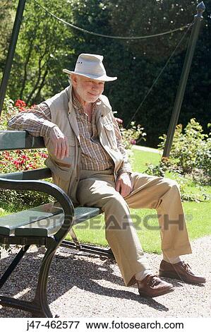 Picture of 70 year old man sitting on a park bench smiling, wearing a ...