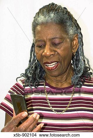 74 year old African American woman with dredlocks in her hair Silhouette Isolated portrait Looking at an open cell phone screen Vertical View Large Photo Image Picture - 74 year old African American woman with dredlocks in her hair Silhouette Isolated portrait Looking at an open cell phone screen Vertical. Fotosearch