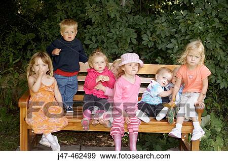 Stock Photo - 8 children under 4, sitting together on a park bench. Fotosearch