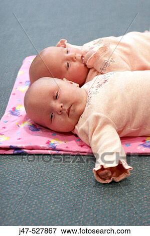 8 week old baby girls twins, matching in pink, lying on their playmat View Large Photo Image Stock Photo - 8 week old baby girls twins, matching in pink, lying on their playmat. Fotosearch