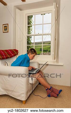 Stock Photo - A 12 year old boy using a laptop computer indoors in the Uk. Fotosearch