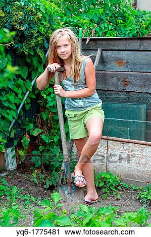 A 12 year old girl standing with a spade in the garden View Large Photo Image Stock Image - A 12 year old girl standing with a spade in the garden. Fotosearch