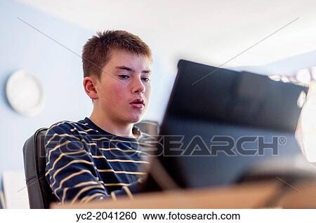 A 13 year old boy looking at his computer tablet in his bedroom. View Large Photo Image Stock Image - A 13 year old boy looking at his computer tablet in his bedroom.. Fotosearch