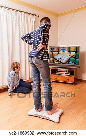A 13 year old boy playing on a Nintendo Wii Fit board with brother watching View Large Photo Image Stock Image - A 13 year old boy playing on a Nintendo Wii Fit board with brother watching. Fotosearch