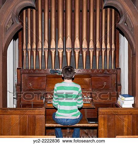 Stock Photograph - A 14 year old boy playing a pipe organ inside a UK church.. Fotosearch