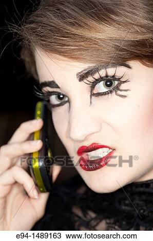 A 19 year old brunette woman with dramaitc make up showing her teeth to a mobile phone. View Large Photo Image Stock Image - A 19 year old brunette woman with dramaitc make up showing her teeth to a mobile phone.. Fotosearch