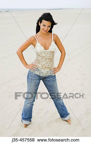 A 20's 30's young woman wearing blue jeans and a lace top, stands on beach barefoot with hands on her hips View Large Photo Image Stock Photo - A 20's 30's young woman wearing blue jeans and a lace top, stands on beach barefoot with hands on her hips. Fotosearch