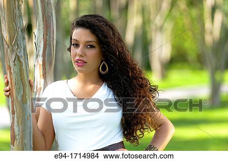 A 21 year old brunette woman wearing a short white dress standing near trees in a garden View Large Photo Image Picture - A 21 year old brunette woman wearing a short white dress standing near trees in a garden. Fotosearch