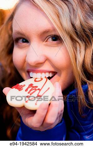 A 22 year old blond woman eating a cookie smiling at the camera. View Large Photo Image Picture - A 22 year old blond woman eating a cookie smiling at the camera.. Fotosearch
