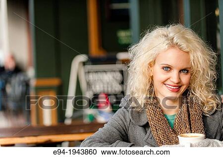 A 22 year old blond woman sitting at an outdoor cafe with a cup of coffee in the winter. View Large Photo Image Stock Image - A 22 year old blond woman sitting at an outdoor cafe with a cup of coffee in the winter.. Fotosearch