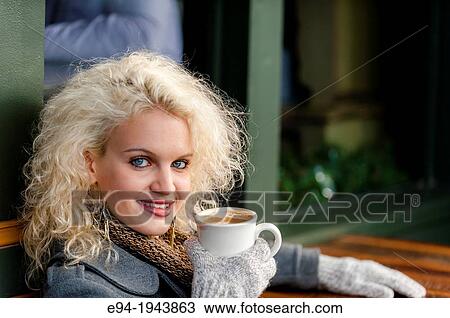 A 22 year old blond woman sitting at an outdoor cafe with a cup of coffee in the winter. View Large Photo Image Stock Image - A 22 year old blond woman sitting at an outdoor cafe with a cup of coffee in the winter.. Fotosearch